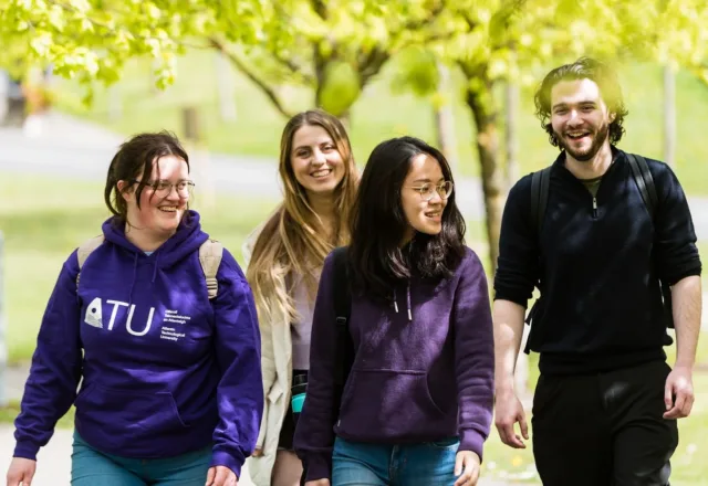 A group of students laughing while walking around the campus