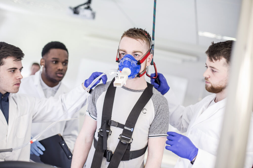 Sports science students measure athletes performance - athlete wearing face mask