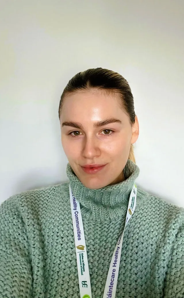 Woman in green jumper with hair tied up