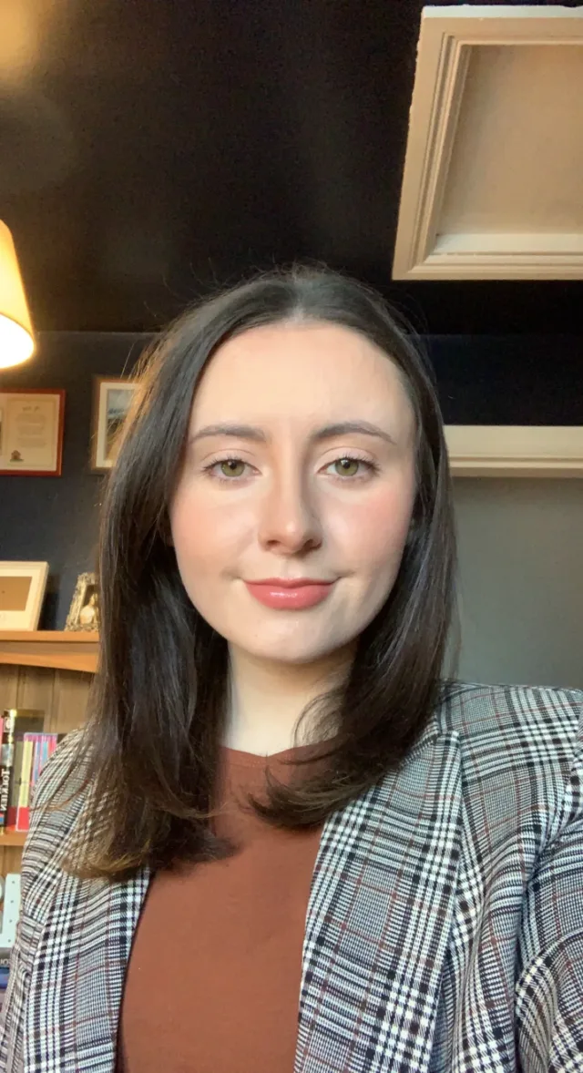 Woman in checked blazer with brown hair.