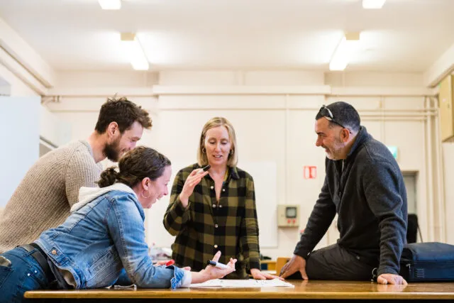 Four students brainstorm around a table in classroom