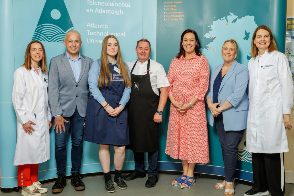 Chef Neven Maguire stands centre with the runner up student. Also in the photo is ATU staff and stakeholders, posed in front of a blue ATU branded backdrop featuring the university's logo and map of Ireland.