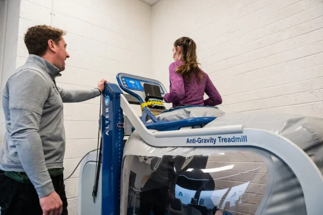 Girl running on a treadmill with coach beside her