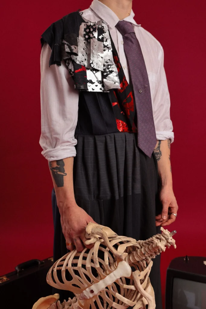 Shot from the neck down in an Upcycled pinstripe polyester outfit holding a skeleton model