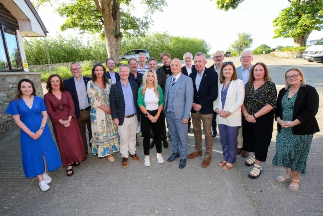 Groupshot of members from Atlantic Technological University and Ulster University stand in a semi circle smiling.