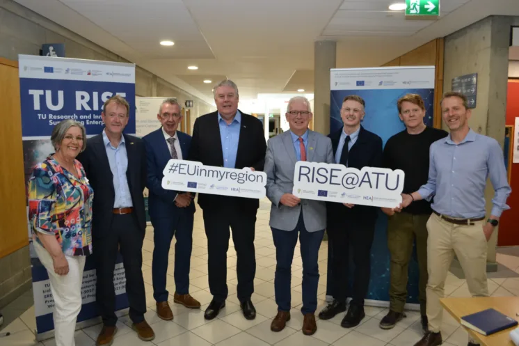 Group of ATU staff and stakeholders smile holding two signs that read #EUinmyregion and RISE@ATU.