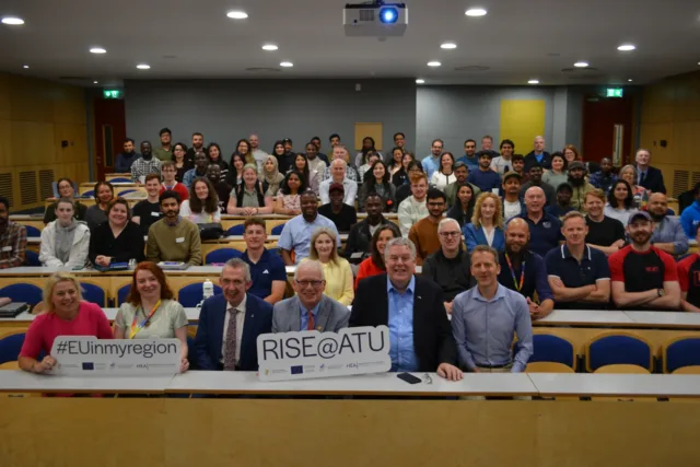 Group of researchers, staff, speakers sit in a lecture theatre, with Ciaran Mullooly (MEP), and Bobbie Baker (NWRA) at the RISE@ATU Summer School.