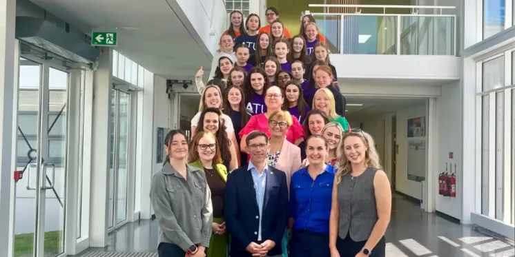 Group of students and staff stand on a staircase smiling