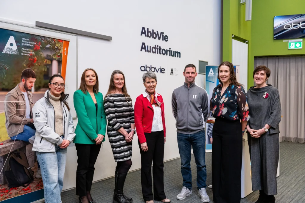 (L-R) Nicole Gallagher, Lesley Ann Armstrong, Finola Howe, Orla Flynn, Dwayne Kelly, Michelle Mc Nulty and Michelle Glacken stand at top of lecture hall in front of white wall with navy letters on the wall 'Abbvie Auditorium' and the abbvie and ATU logos beneath that.