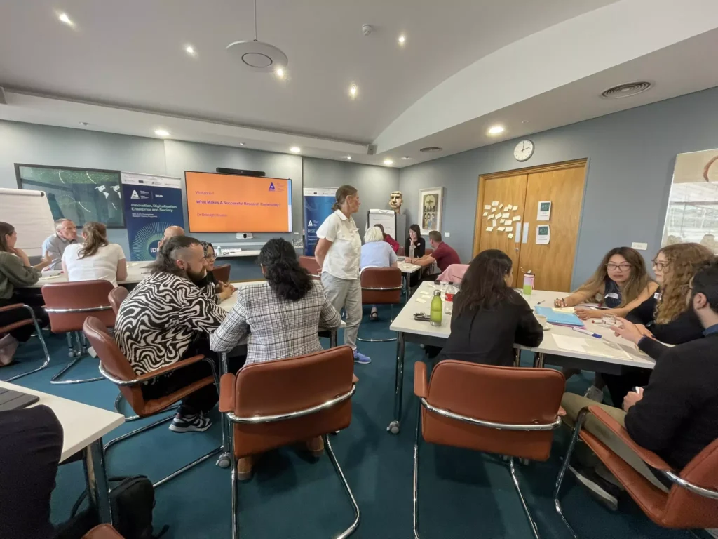 Participants are seated in small groups during a research workshop, engaging in discussion and collaborative tasks.