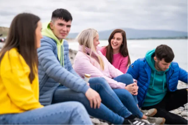 5 students are sitting by a lake laughing together