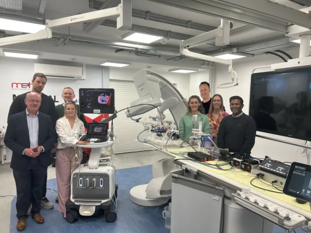 Group of people standing beside medical equipment in a lab.