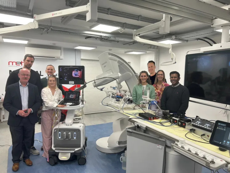 Group of people standing beside medical equipment in a lab.