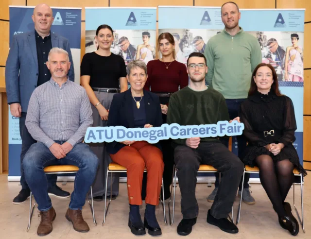 A group of people posing for a photo. Two in the middle are holding an ATU Donegal Careers Fair sign