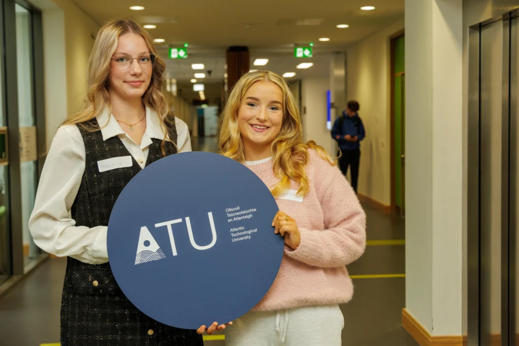 Two students holding a circular blue ATU sign