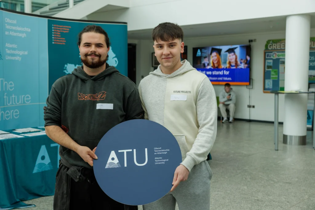 Two students holding a circular ATU sign
