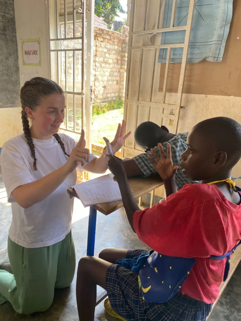 Home Economics Student Teacher working with children in a classroom. Both student and teacher are holing their fingers up counting.