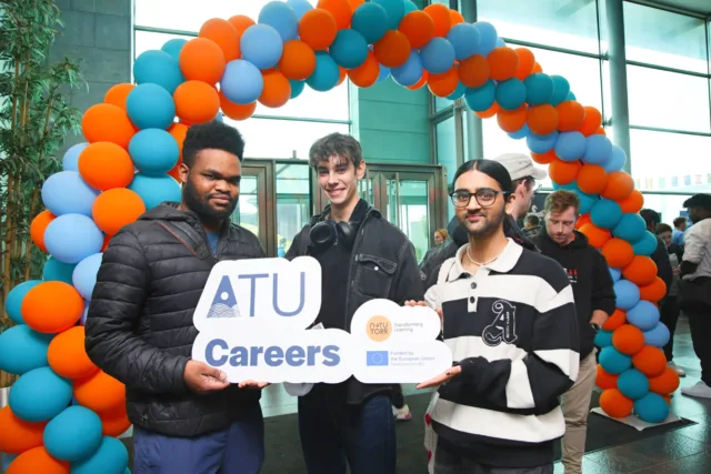 Students with balloon arch standing with handheld signs.