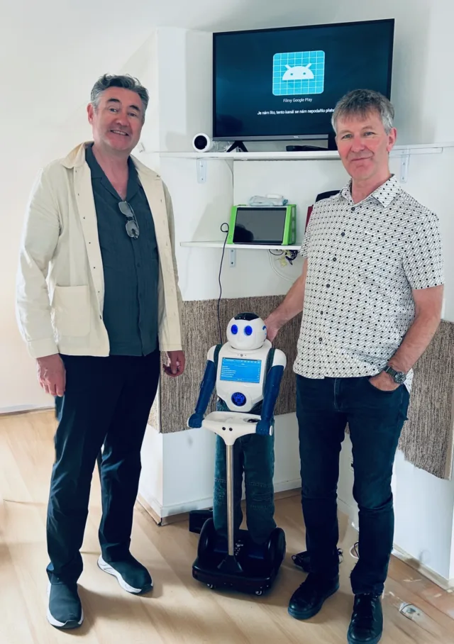 John and Perry are standing between them is a blue and white robot.