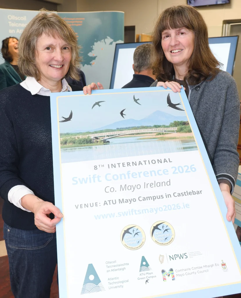 Two ATU staff holding large poster on the Swift conference.