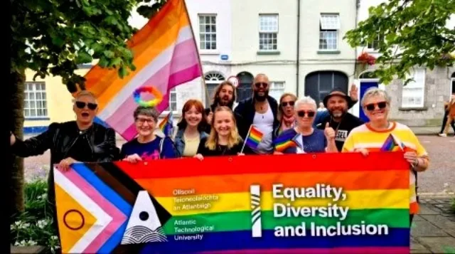 ATU staff and students stand behind a pride banner with ATU logo and Equality Diversity and Inclusion written on it. Some are also holding flags.