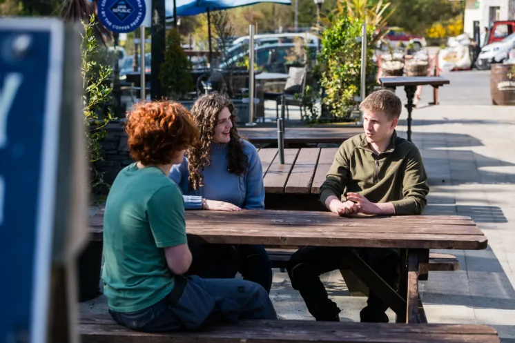 Shot of ATU students talking on wooden bench