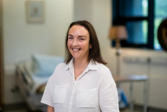 Female mature student standing in a white shirt smilling