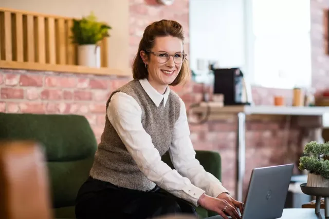 Female sitting typing on a laptop looking at the camera