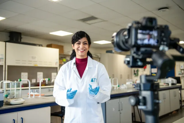 Female in a white coat talking to a camera