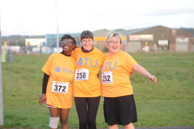 Three people at the ATU Annual Charity 5k in orange ATU T-shirts.