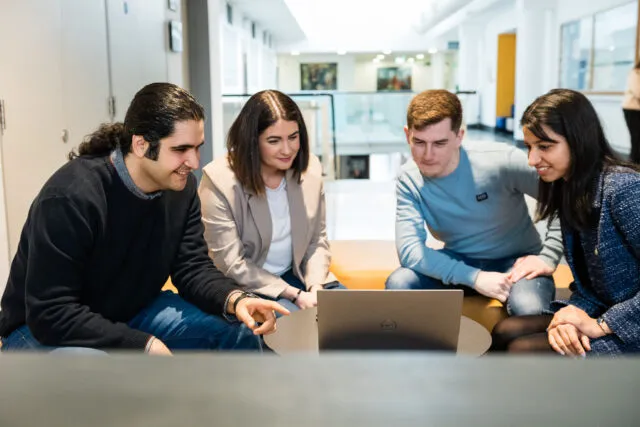 Postgrad Students undertaking a group project around a laptop