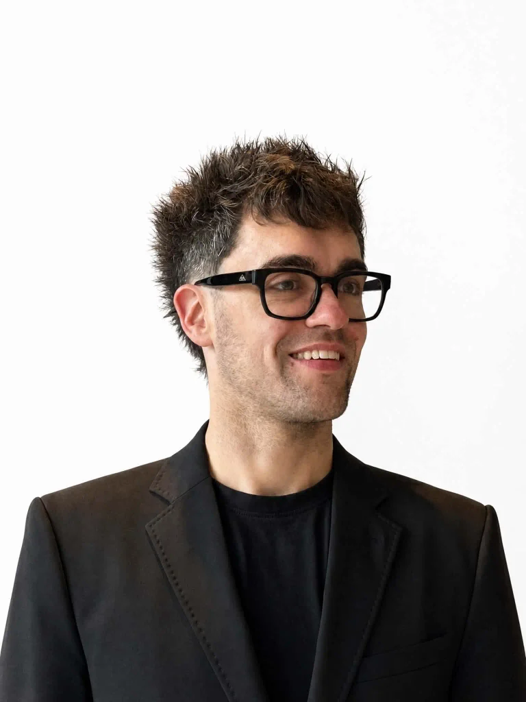 Headshot of Chandler Tyrrell - a man in suit with glasses.