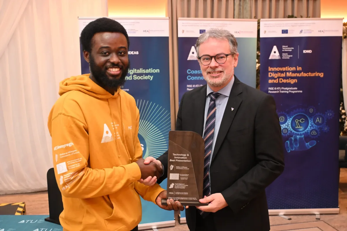 Male student Obed Peprah receiving award from CEO of Research, Innovation, and Engagement