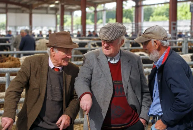 Group of three farmers chatting in mart