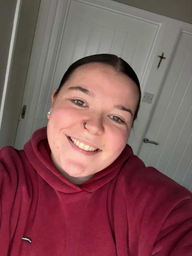 female student smiling in headshot picture wearing a red sweatshirt