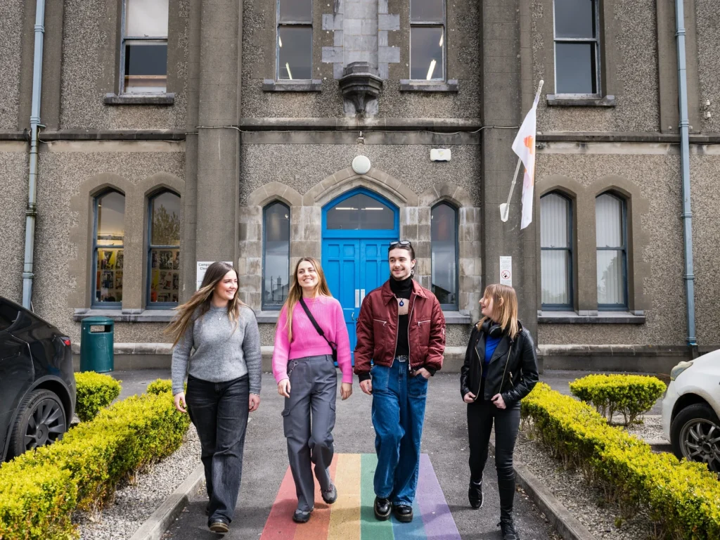 3 female students and 1 male student walking outside Wellpark campus