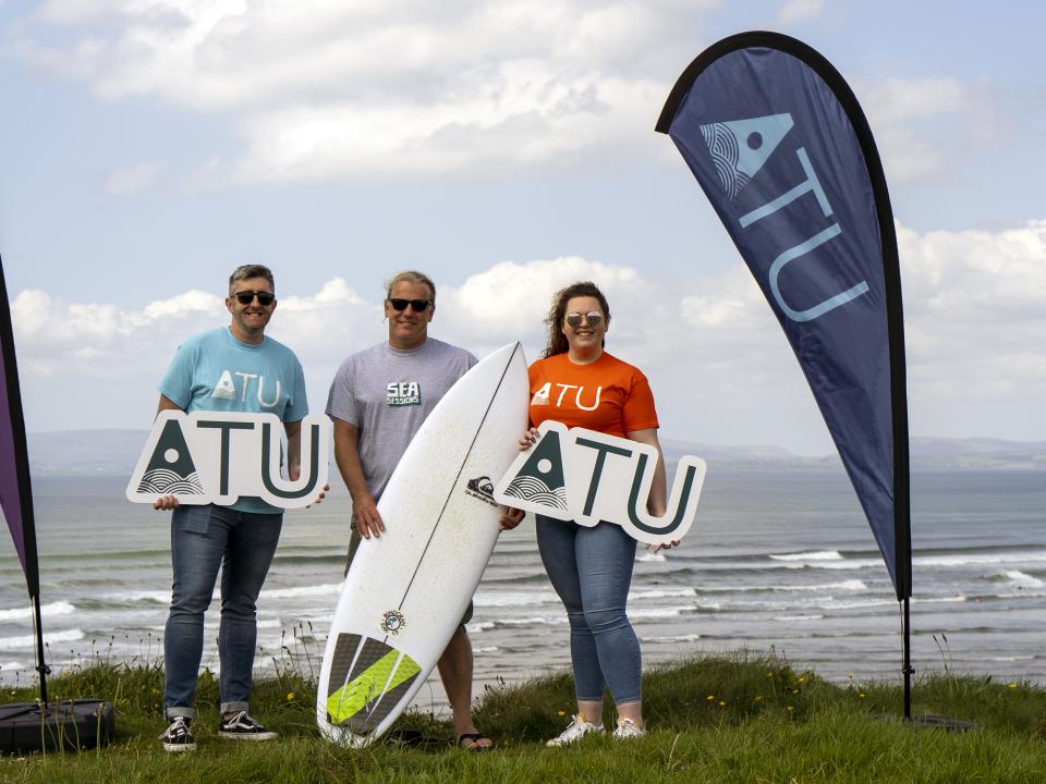 image of 3 people on a beach with STU and Sea Sessions flags
