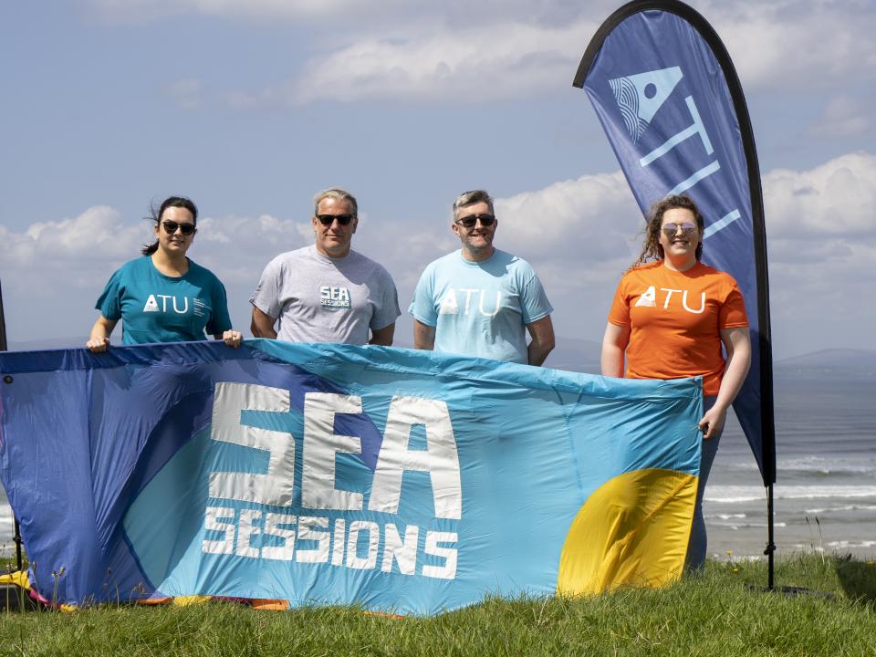 image of four people on beach with ATU and Sea Sessions flags