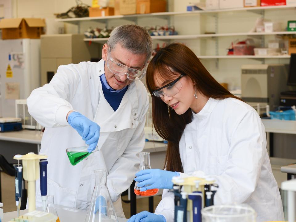 Students in lab coats around beakers