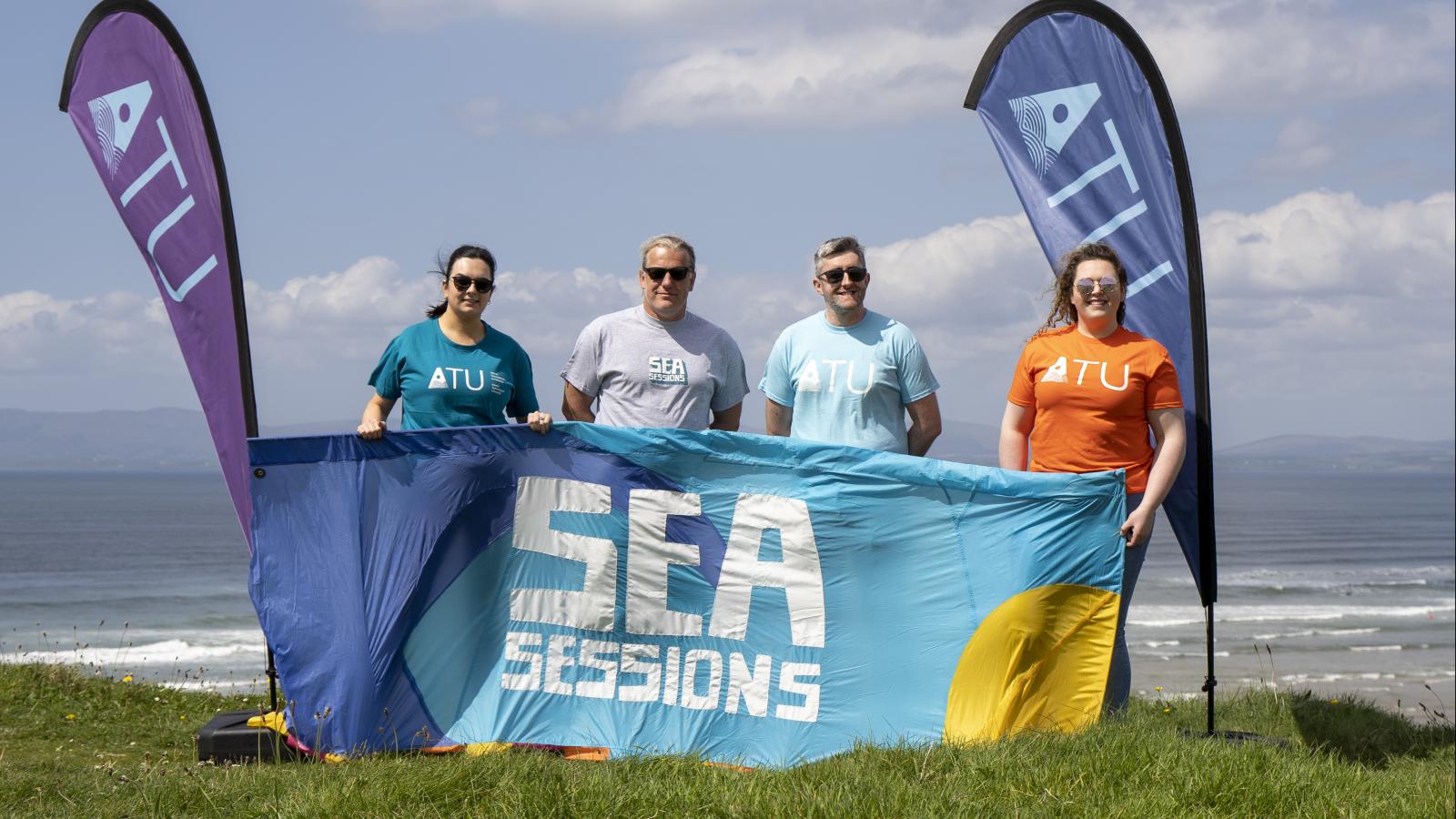 image of four people on beach with ATU and Sea Sessions flags